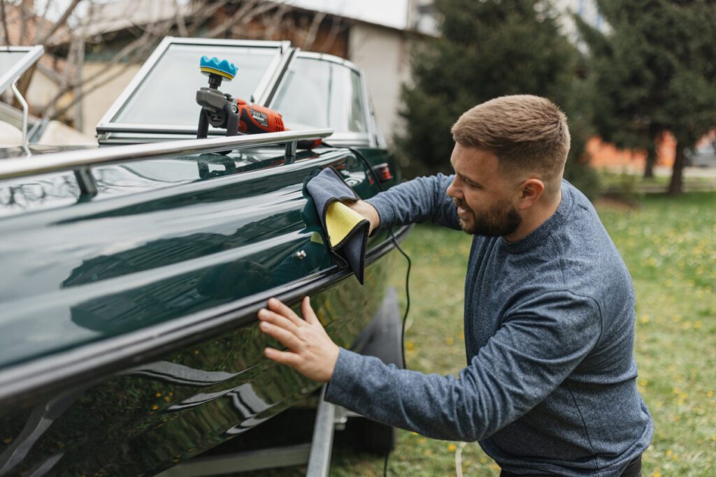 A person is carefully applying a microfiber cloth to the polished surface of a boat, ensuring every detail is perfect and demonstrating dedication to boat care and aesthetics.
