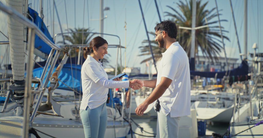 Handshake, travel and cabin crew with people on boat for luxury holiday, guest booking and maritime safety. Captain, client and marina with man and woman on pier for meeting, nautical and harbor