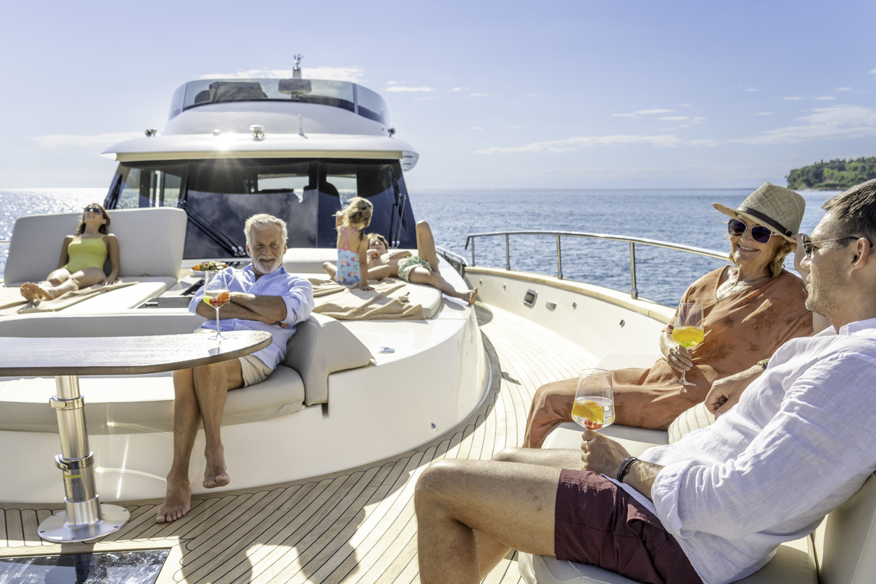 Multigenerational family enjoying cruise on impressive yacht on sunny day. Spending time on front deck. Luxury vacation at sea.