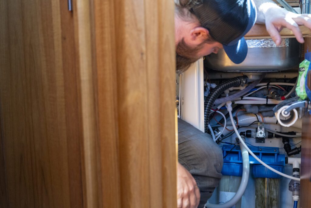 Man inspects engine on sailboat, British Columbia