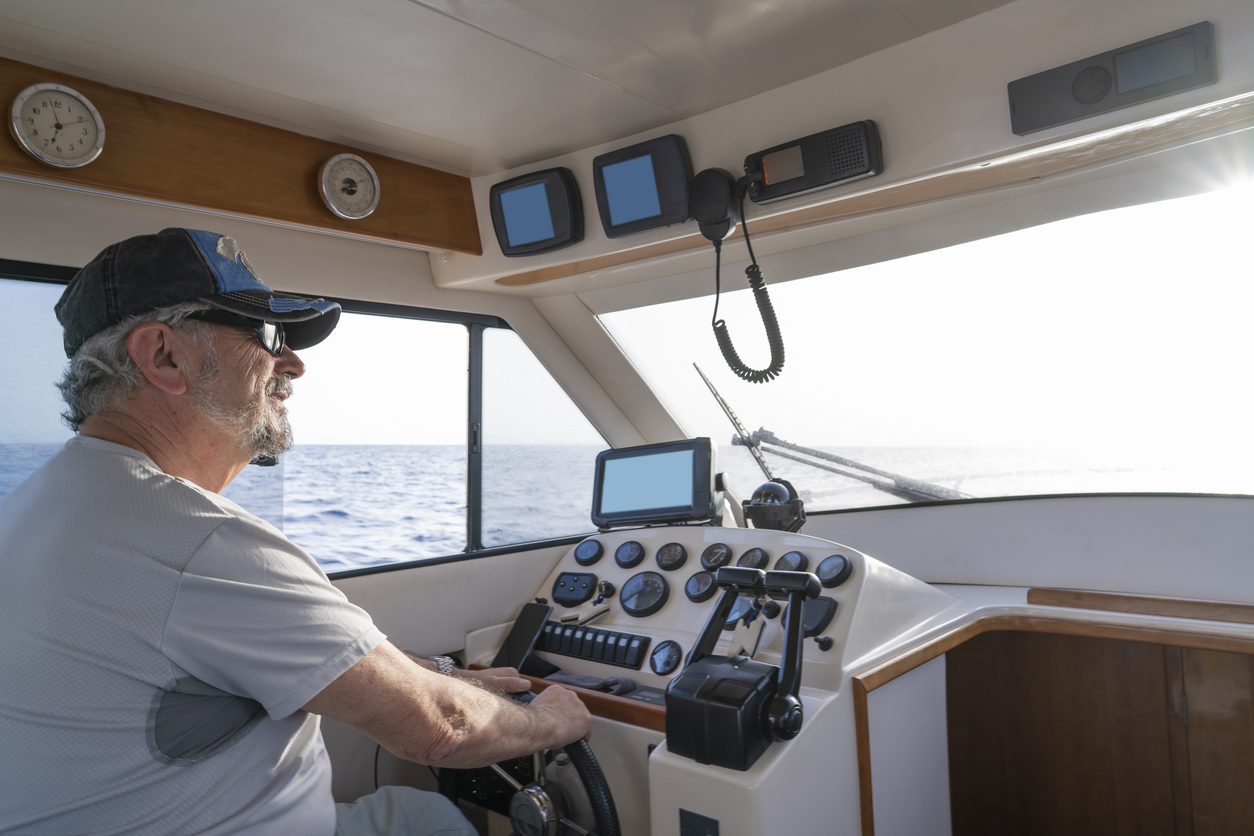 Active senior sailing motorboat happy retirement as sailor captain in indoor yacht
